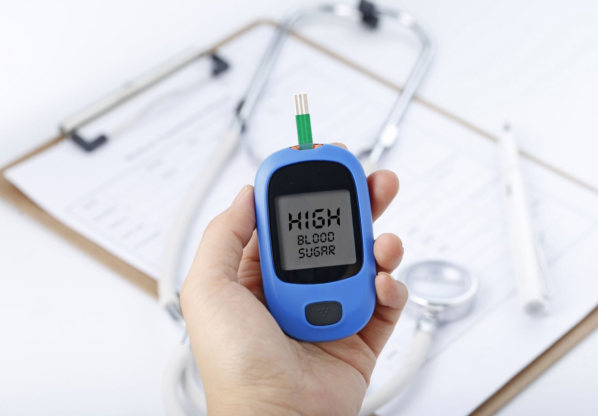 hand-holding-blood-glucose-meter-measuring-blood-sugar-background-is-stethoscope-chart-file2